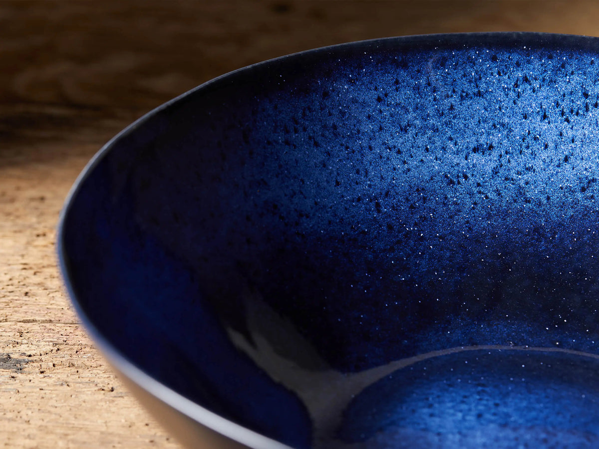 Twilight Serving Bowl with rich indigo reactive glaze, handcrafted in stoneware. Blue interior with slight color variance, set on wooden surface.