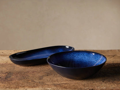 Twilight Serving Bowl with a rich indigo glaze, showcasing a unique speckled pattern. The bowl is slightly curved with a smooth finish.