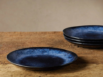 Close-up of a Twilight Salad Plate, showcasing its indigo reactive glaze with lighter specks, like a starry night. Beige background.