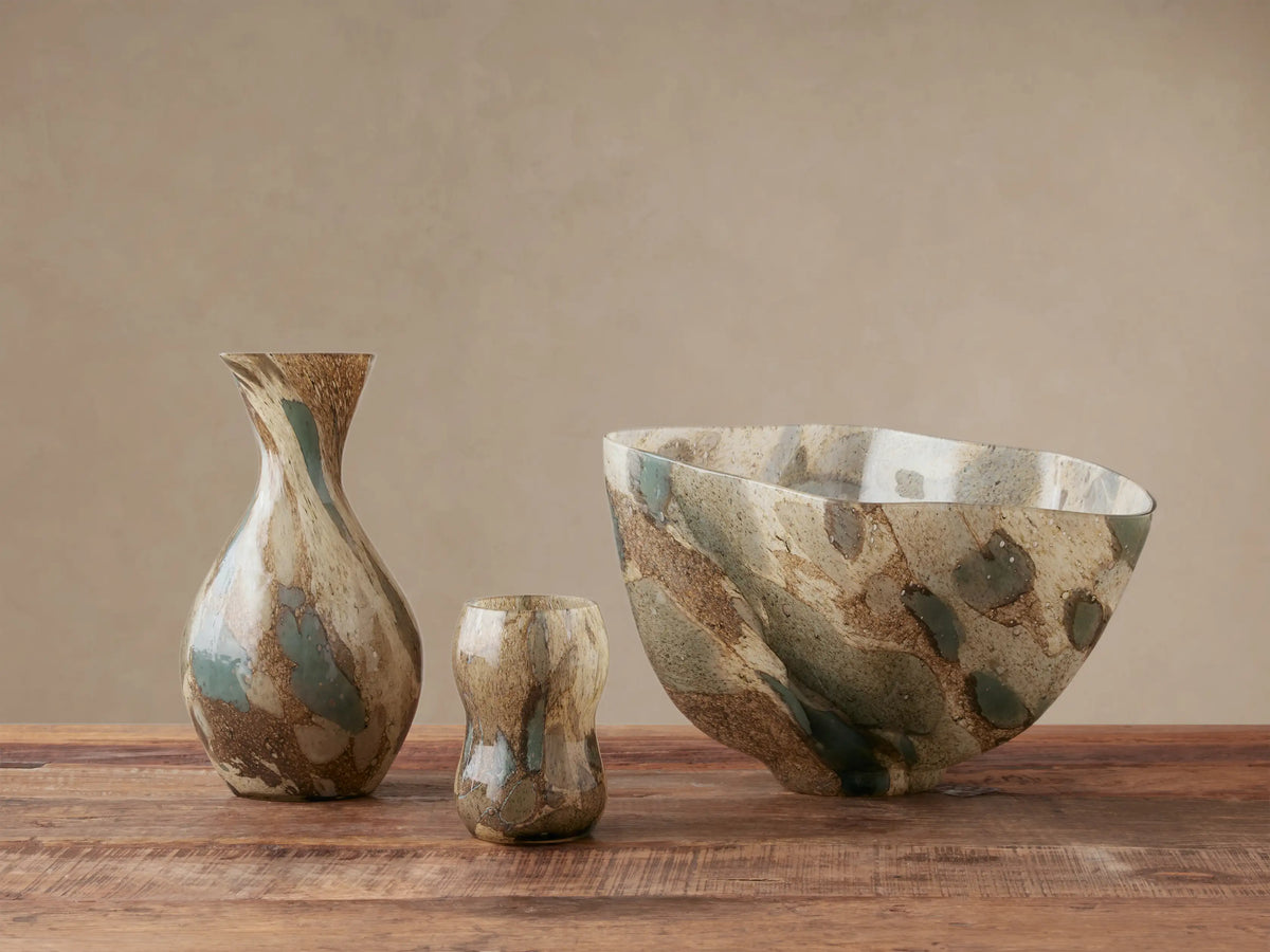 Andromeda Organic Bowl, mouth-blown glass with organic shape, swirling earthy blue, green, brown, and gray patterns on wood.