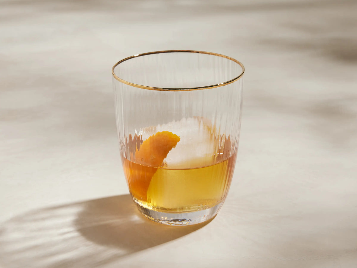 Clear Anisa Double Old Fashioned Glass, close-up, featuring vertical ribbed texture and a hand-painted gold rim.