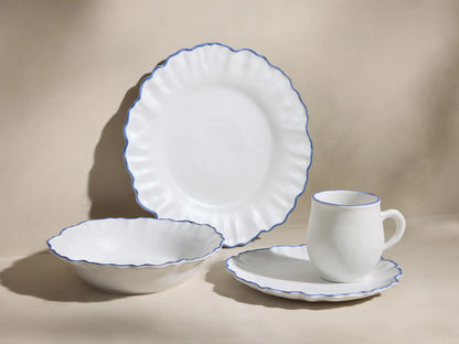 Capuchos Dinnerware: white matte large plate, pasta bowl, mug, and salad plate, all with blue ruffled edges.