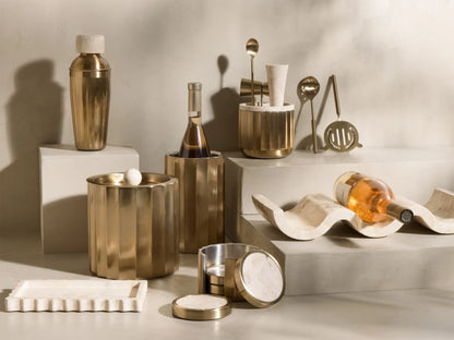 Front view of Brass Dayan Bar Tools: strainer, double jigger, muddler, two bar spoons, and fluted holder with concrete lid.