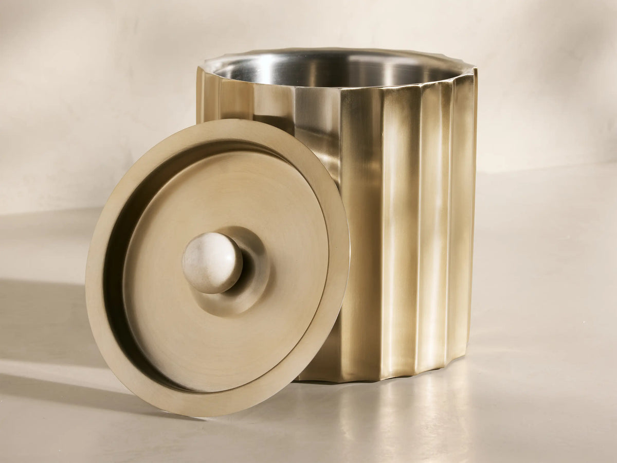 Close-up of the gold Dayana Ice Bucket, a fluted brass-finish stainless steel design with a white marble ball and brushed interior.