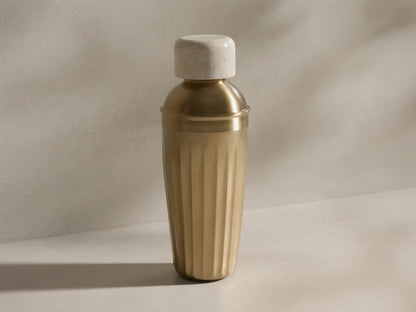 Front view of the Dayana Cocktail Shaker, featuring a light marble cap and a fluted brass-finished body.