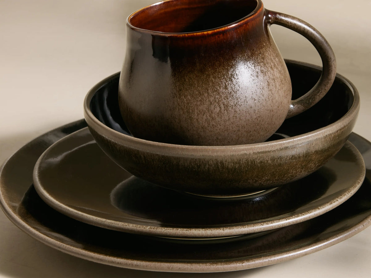 Chocolate and mocha Hearthline Dinnerware With Cereal Bowls (Set of 16), featuring reactive glaze mugs, bowls, and plates.