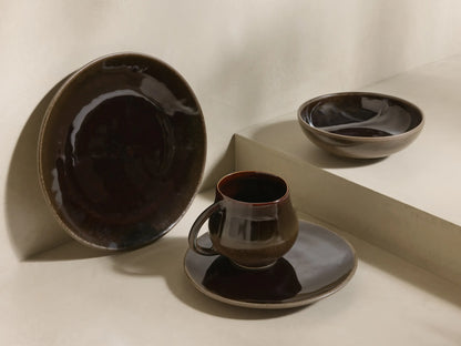Angled view of stacked Hearthline Dinnerware With Cereal Bowls (Set of 16) in rich chocolate and mocha reactive glaze.