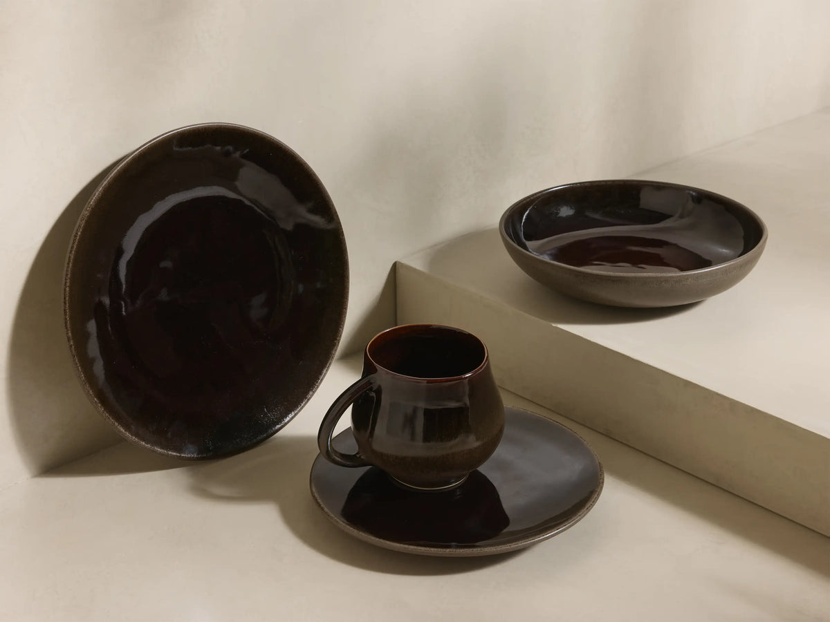 Close-up of stacked brown speckled Hearthline Dinnerware With Pasta Bowls, featuring a glossy dark brown mug.