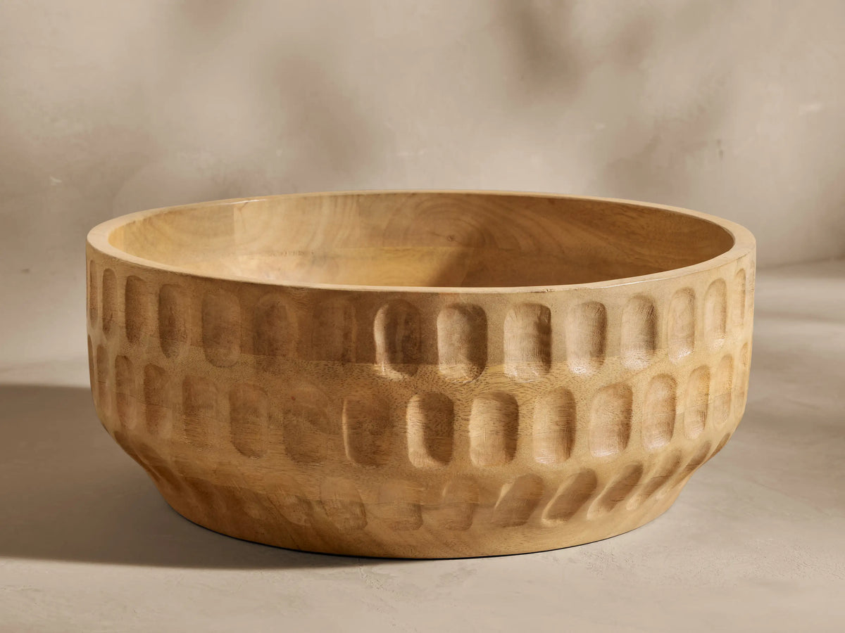 Kanga Bowl of natural mango wood, carved with vertical oval textures, set against a light, plain background.