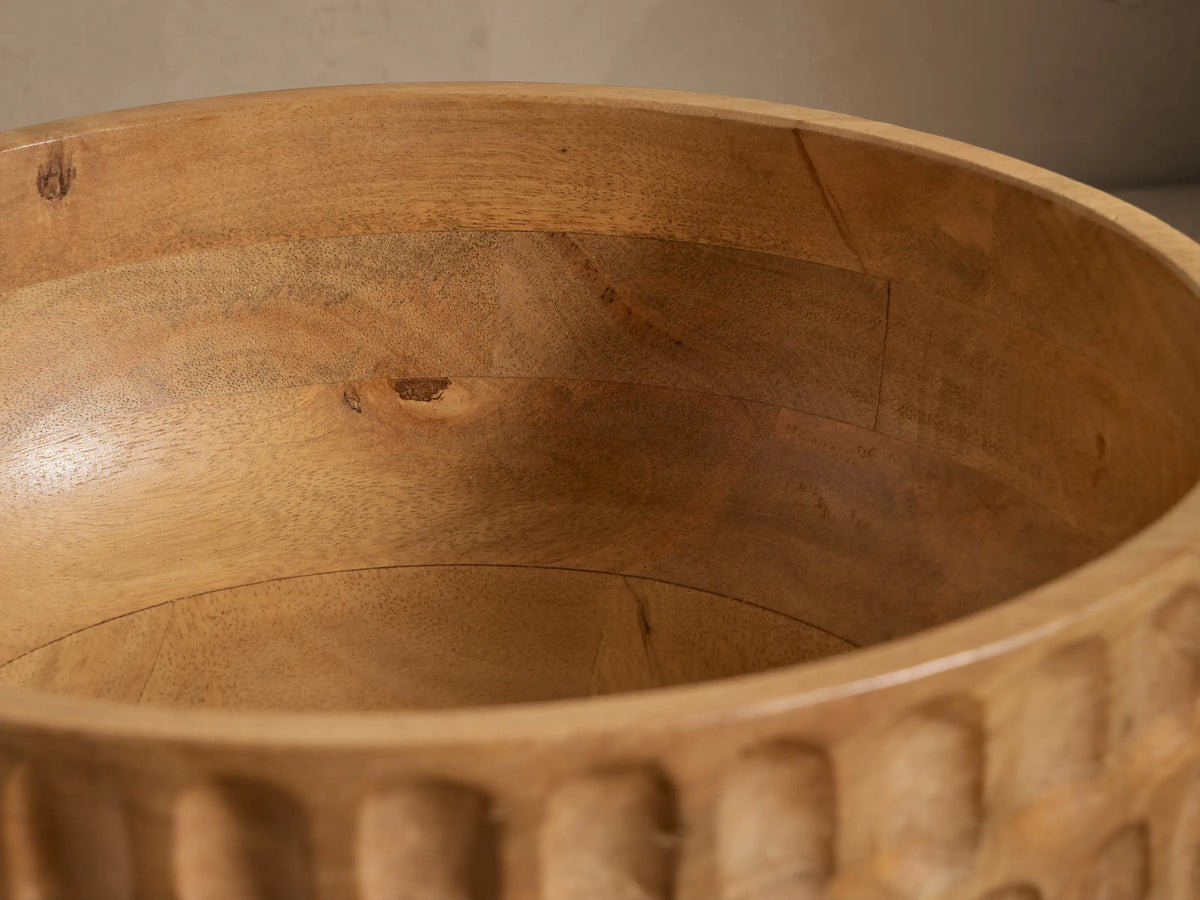 Kanga Bowl of natural mango wood, carved with vertical oval textures, set against a light, plain background.