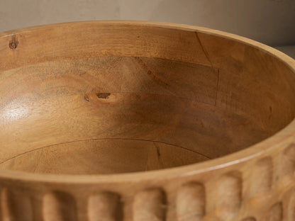 Kanga Bowl of natural mango wood, carved with vertical oval textures, set against a light, plain background.