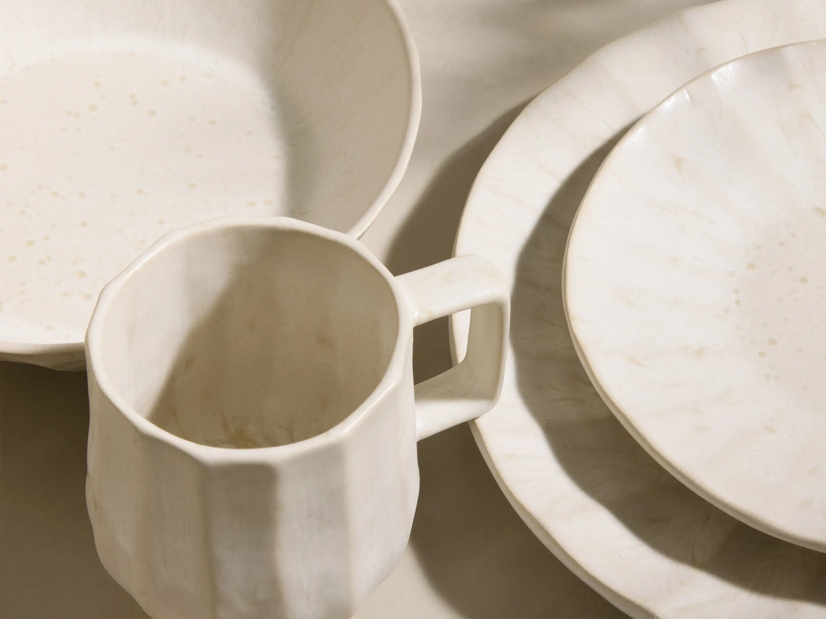 Full set of cream Saskia Dinnerware With Pasta Bowls (Set of 16) with fluted texture, displayed on light risers.