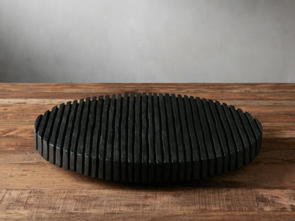 Oval black Slat Lazy Susan made of textured vertical reclaimed wood slats, resting on a rustic wooden table.