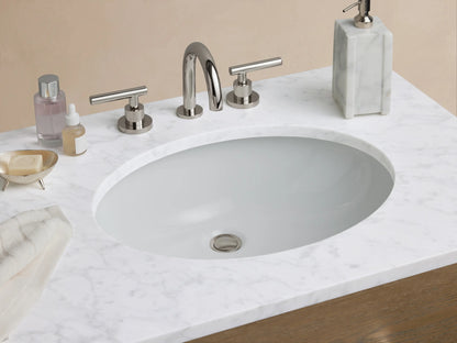 Calista Double Vanity in oak wood with six drawers and silver handles, stone top with two sink spaces, set against a neutral wall.