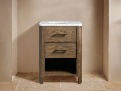 Calista Powder Vanity. Dark oak wood vanity with white marble top, two drawers, open shelf with towels, dark bronze faucet.