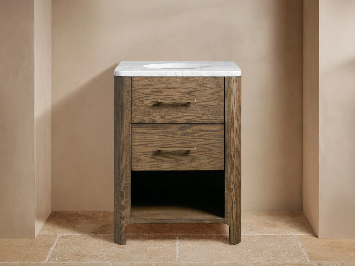 Calista Powder Vanity made of oak wood with two drawers, white stone top, brass hardware, and an oval undermount sink.