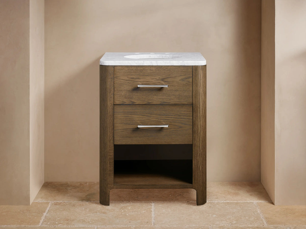 Calista Powder Vanity with oak frame, stone top, undermount sink, and two drawers, set in a neutral-toned bathroom scene.
