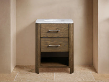 Calista Powder Vanity with oak frame, stone top, undermount sink, and two drawers, set in a neutral-toned bathroom scene.