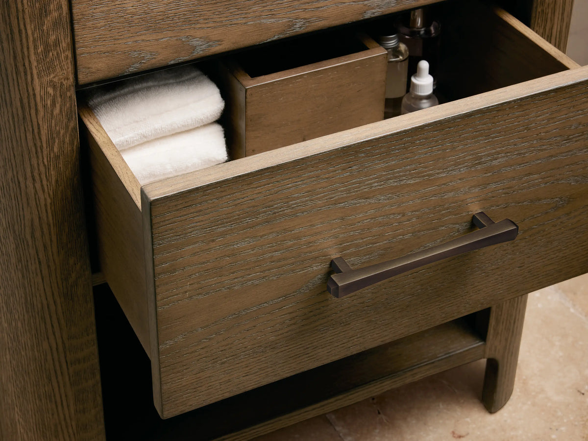 Close-up of Calista Powder Vanity top: multi-toned veined marble, white oval sink, antique bronze faucet, soap & decor.