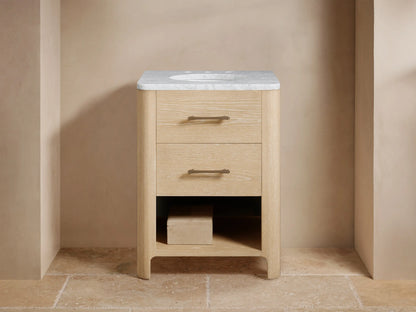 Calista Powder Vanity with light oak finish, topped with Carrara or Calacatta Viola marble. Features brass hardware, marble backsplash.