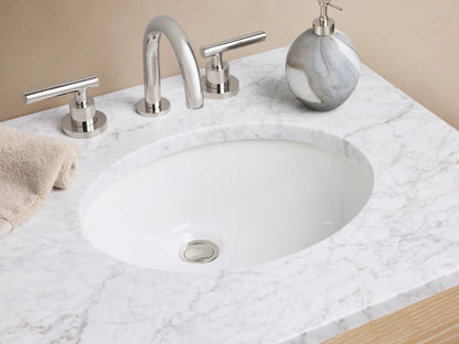Calista Powder Vanity with oak wood finish, marble stone top, two drawers, and an open shelf underneath, placed against a beige wall.