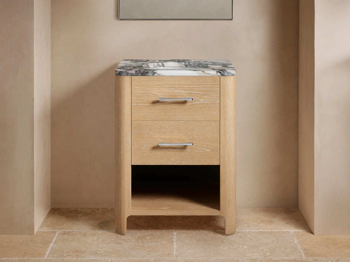 Calista Powder Vanity with oak wood finish, two drawers, and a black and white marble top. Sink with rolled towels beneath.