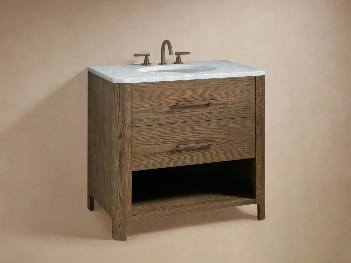 Close-up of Calista Single Vanity's open oak wood drawer with bronze pull, showing folded white towels and storage items inside.