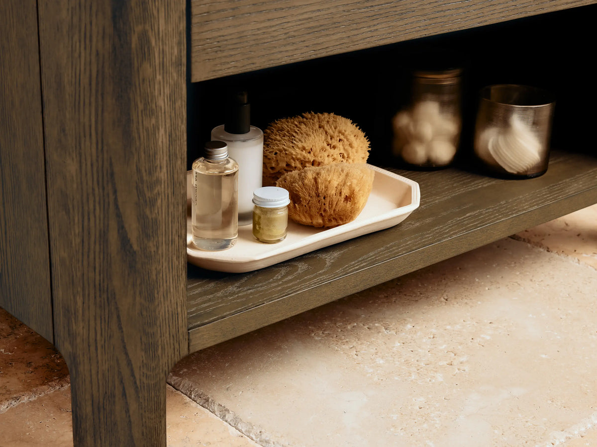 Alt text: Close-up of the Calista Single Vanity drawer open to reveal bath accessories. Features wood grain texture and sleek metal handles.