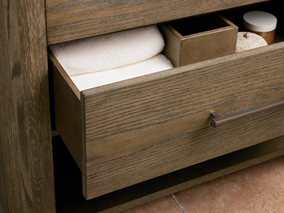 Calista Single Vanity close-up: white oval sink with bronze drain, bronze widespread faucet, and richly veined brown/grey marble top.