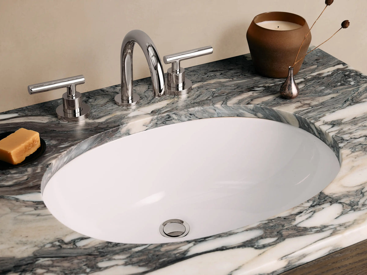 Calista Single Vanity with a brown oak wood body, marble top, two faux drawers with metallic handles on a tiled floor.