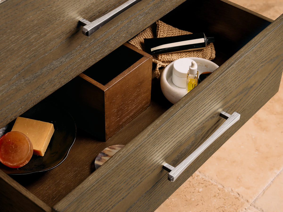 The Calista Single Vanity features a white oval ceramic undermount sink on a marbled stone top with chrome faucets and accessories.