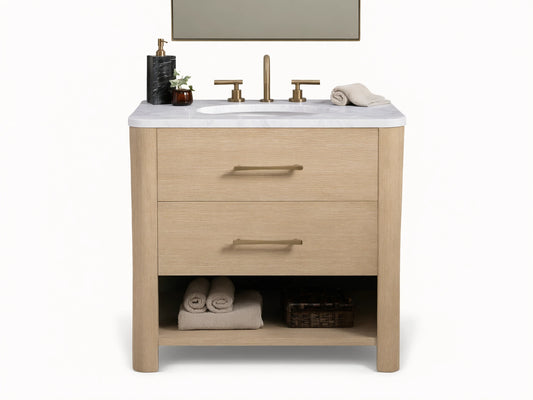Calista Single Vanity with light oak finish, white marble top, oval sink, dual brass faucets, and storage shelf below.