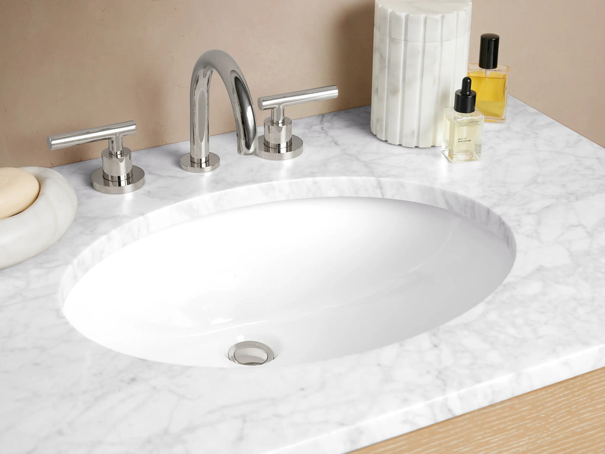 Calista Single Vanity with light oak wood finish and two drawers, topped with a white stone countertop featuring an oval sink.