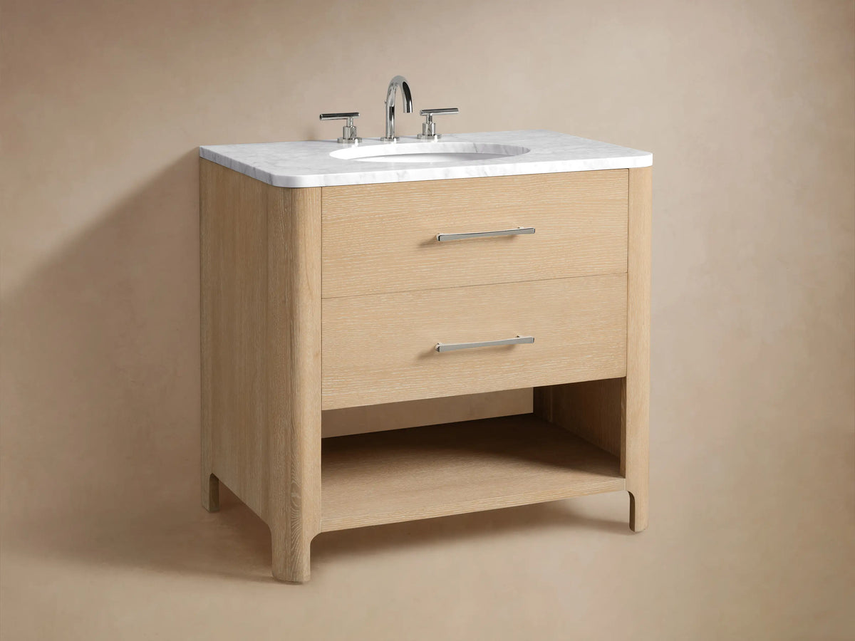 Alt text: Close-up of the Calista Single Vanity lower shelf, made of light oak wood, displaying folded white towels and a natural sponge on a stone floor.