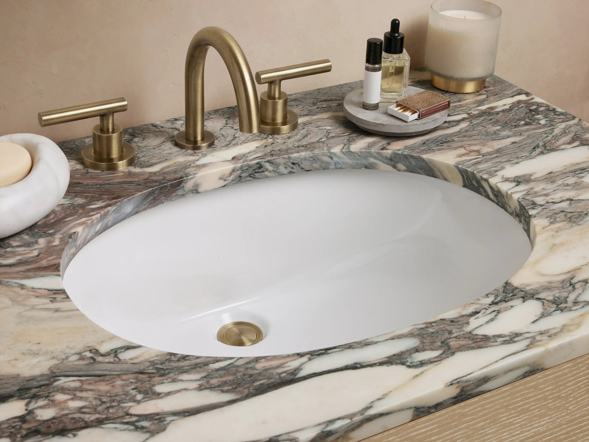 Calista Single Vanity with a marble stone top and oak wood body. Features two drawers with brass handles and a faux top drawer.