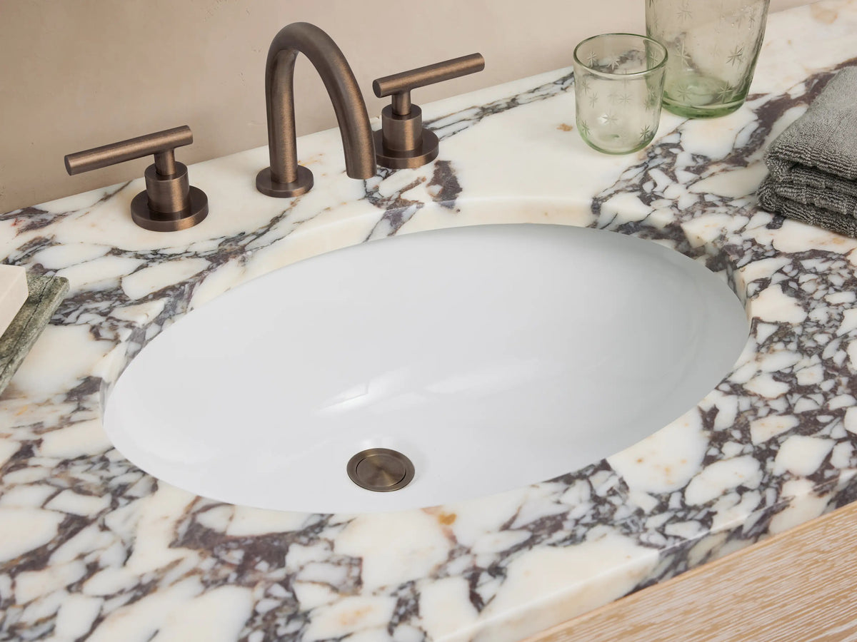 Calista Wide Single Vanity: Light oak wood with grain, 6 drawers, dark handles, white/grey marble top, open shelf.