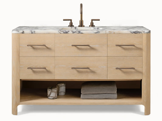 Calista Wide Single Vanity: light oak wood, 6 drawers with dark pulls, white Carrara marble top, dark faucet, open shelf below.