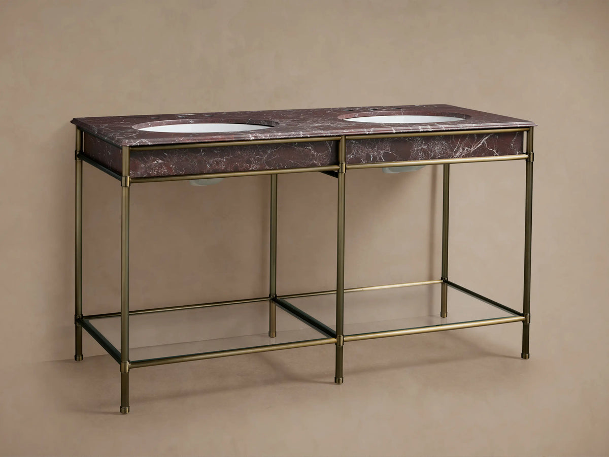 Close-up of Chelsea washstand's Antique Brass frame, glass shelf holding marble tray, bronze jar, oil bottle.