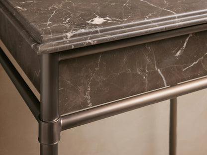 Lower glass shelf of Chelsea Powder Washstand in bronze finish, with folded beige towels, amber bottle, and jar.