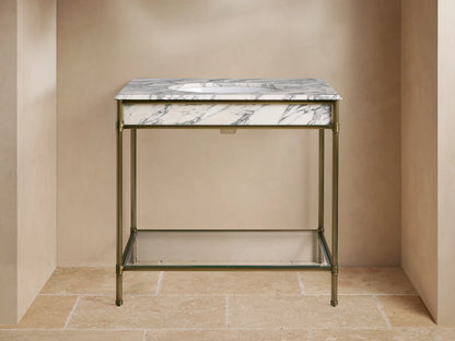 Chelsea Single Washstand: White veined marble top, undermount sink, gold widespread faucet, antique brass frame, glass shelf with towels.
