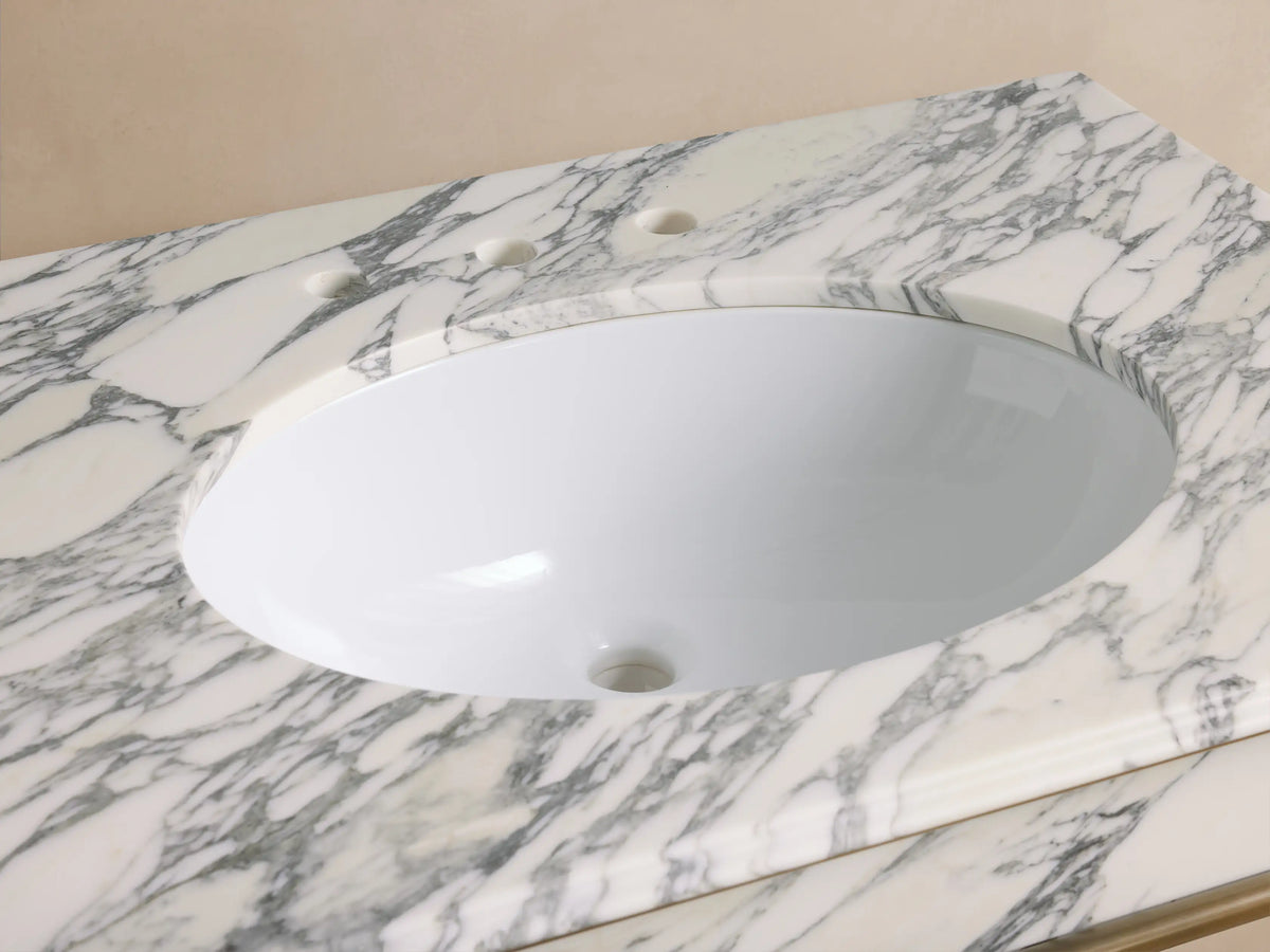 Chelsea Single Washstand close-up: white oval undermount sink in veined white marble top, antique brass faucet.