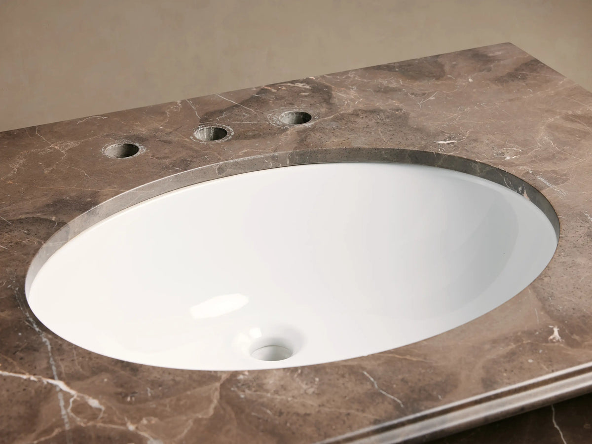 Chelsea Single Washstand. Oval white sink, bronze faucet, and veined brown marble countertop with soap, dispenser, & flowers.