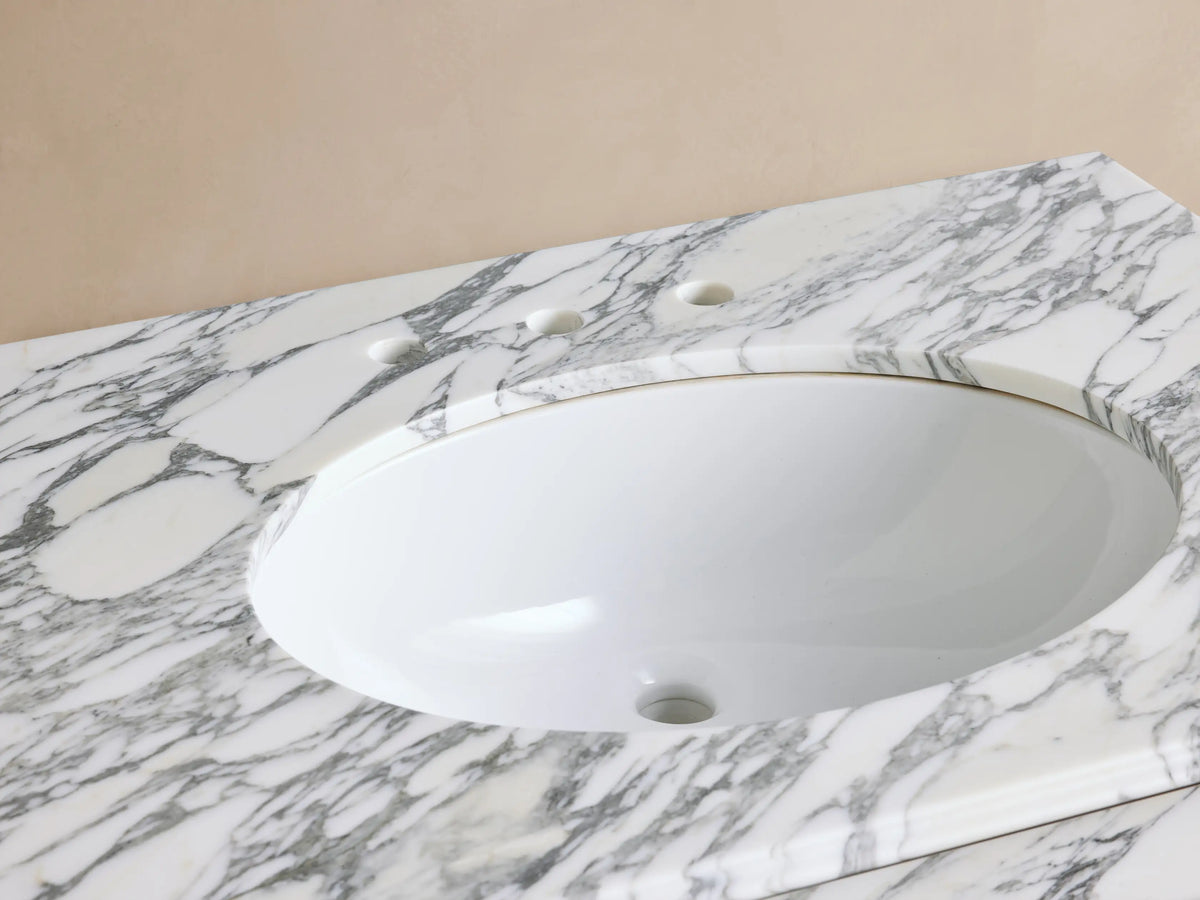 Close-up of Chelsea Single Washstand. White oval sink in veined marble counter with bronze widespread faucet & soap.