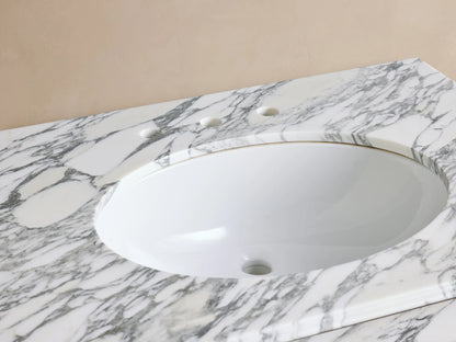Close-up of Chelsea Single Washstand. White oval sink in veined marble counter with bronze widespread faucet & soap.