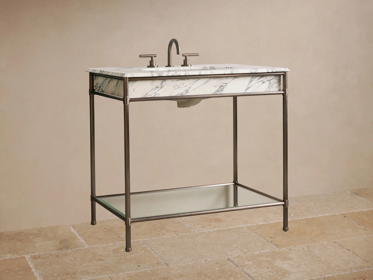 Chelsea Single Washstand close-up: Dark metal frame, clear glass shelf, and three stacked white towels.