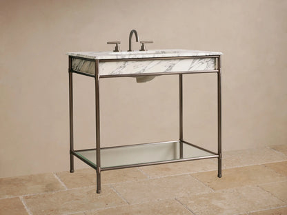 Chelsea Single Washstand close-up: Dark metal frame, clear glass shelf, and three stacked white towels.