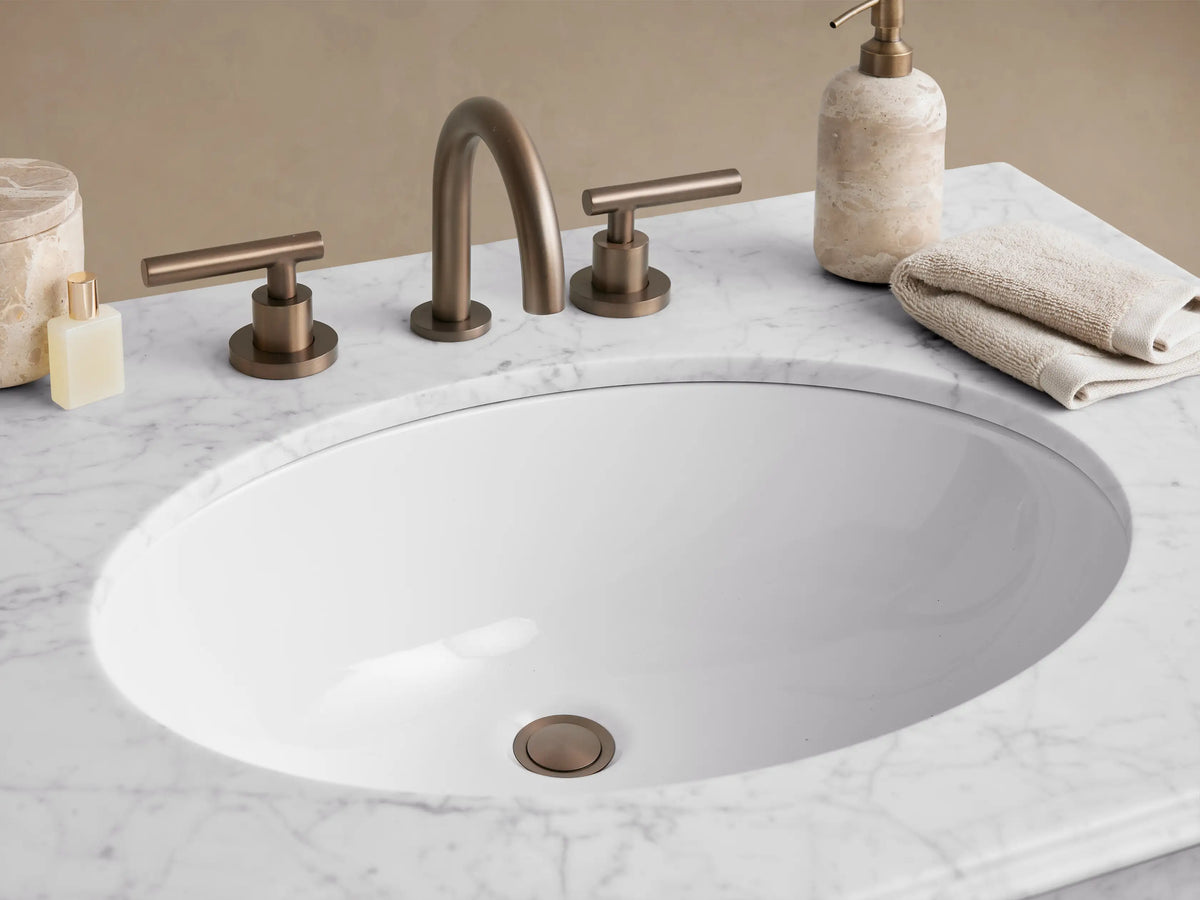 Chelsea Single Washstand with white marble top, oval sink, and an Antique Bronze finish metal frame with a clear glass shelf.