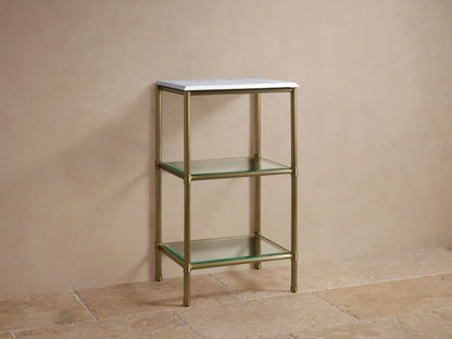 Chelsea Short Etagere with antique brass frame, Carrara marble top, two glass shelves, and decorative items in a beige setting.