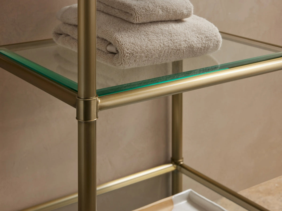 Chelsea Short Etagere with a white Carrara marble top, gold stainless steel frame, displaying folded towels and a dish on the top.