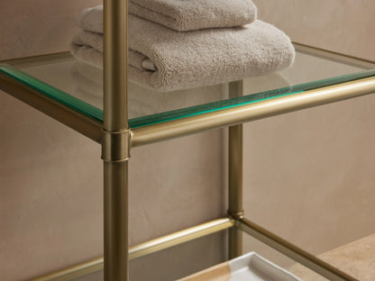 Chelsea Short Etagere with a white Carrara marble top, gold stainless steel frame, displaying folded towels and a dish on the top.
